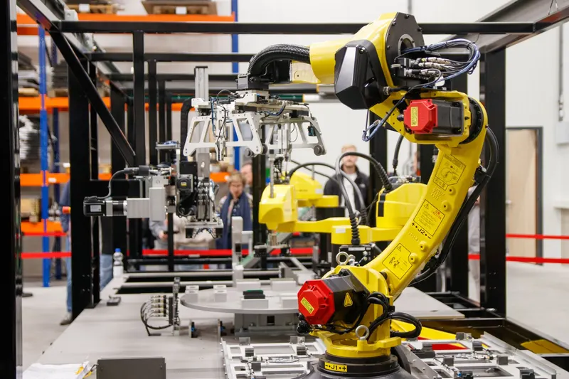 Illustrative photo: yellow industrial robotic arm in a factory test cell